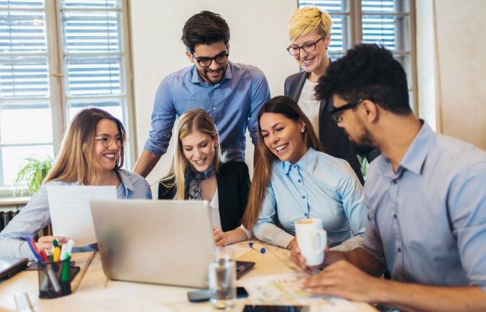 A group of people gathering around a computer as they work together collaboratively