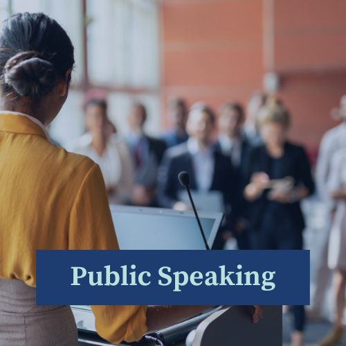 A woman standing in front of a seated audience as she addresses them from a lecturn