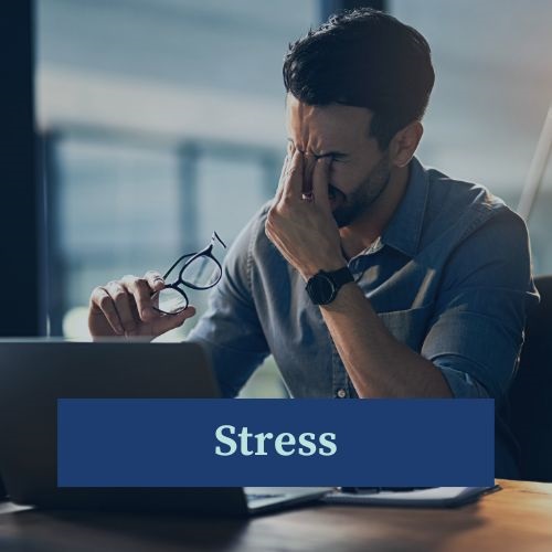 A man sitting at a computer rubbing his eyes struggling with stress